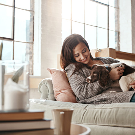 Smiling woman relaxing on couch with dog