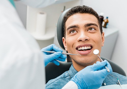 Man with dark hair in denim shirt about to undergo dental exam
