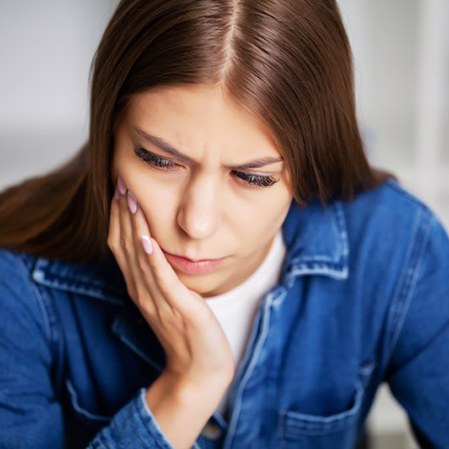 Young woman holding her cheek in pain