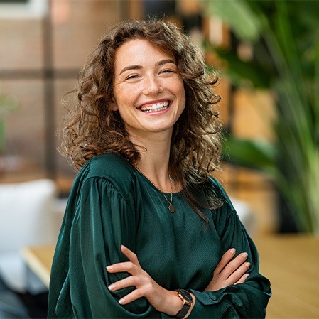 Woman in green shirt smiling with arms folded