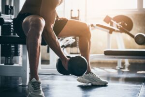 Neck down view of man lifting weights with harm